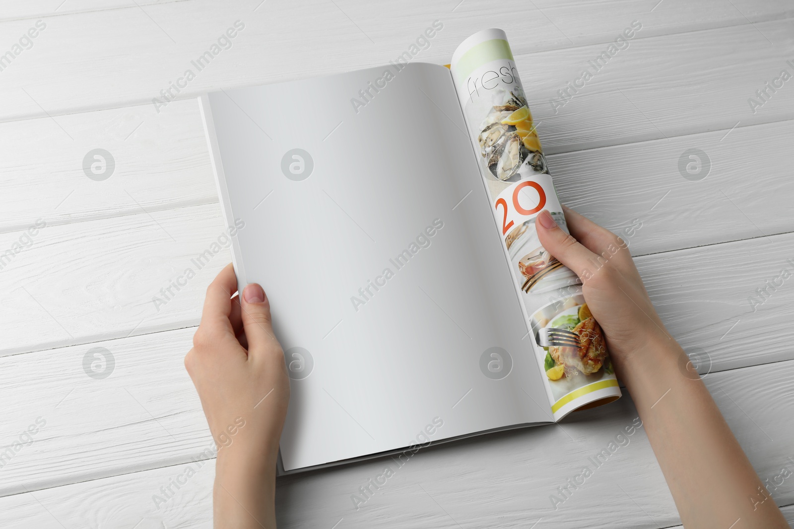 Photo of Woman reading magazine at white wooden table, top view. Mockup for design