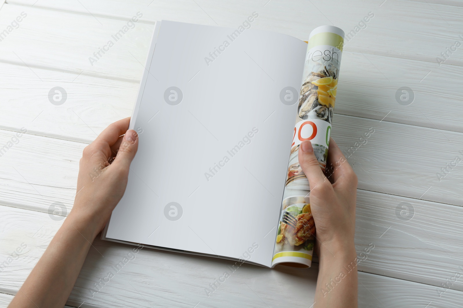 Photo of Woman reading magazine at white wooden table, closeup. Mockup for design