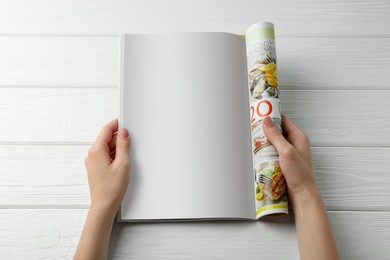 Photo of Woman reading magazine at white wooden table, top view. Mockup for design