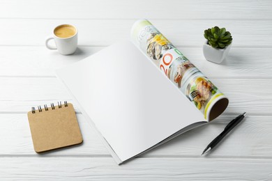 Photo of Open magazine with blank page, coffee, plant and stationery on white wooden table. Mockup for design