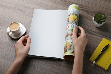 Woman reading magazine at wooden table, closeup. Mockup for design