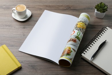 Photo of Open magazine with blank page, coffee, plant and stationery on wooden table. Mockup for design