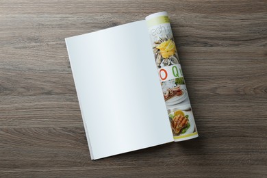 Open magazine with blank page on wooden table, top view. Mockup for design