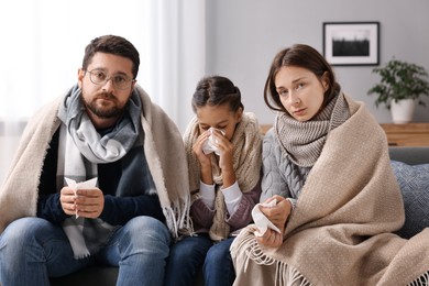 Photo of Cold symptom. Family suffering from fever on sofa at home