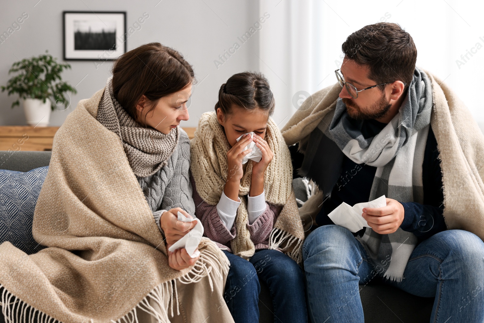 Photo of Cold symptom. Family suffering from fever on sofa at home