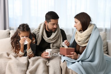 Cold symptom. Family suffering from fever on sofa at home