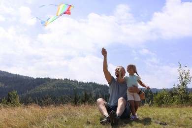 Happy father with daughter flying kite at field