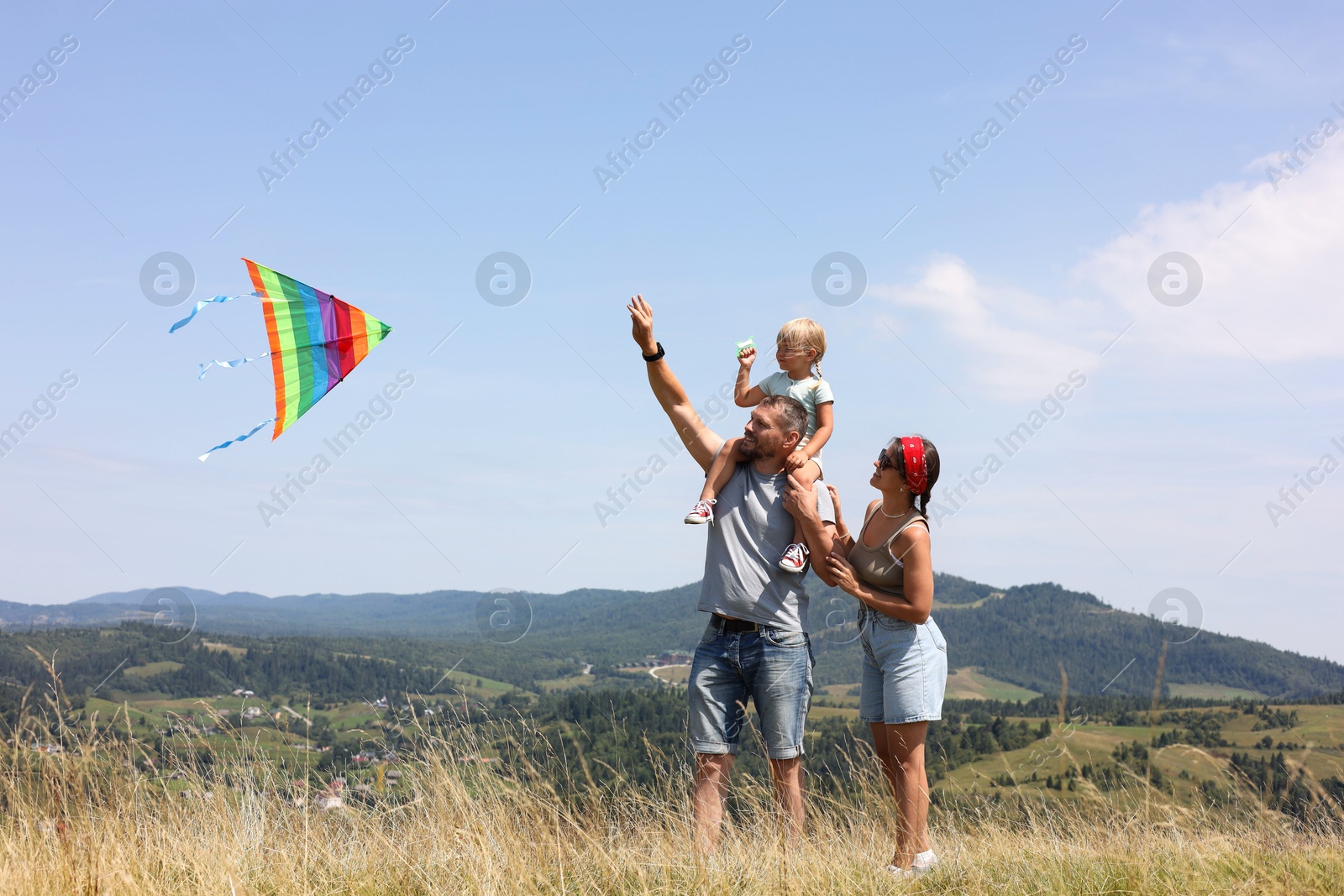 Photo of Happy family flying kite at field under blue sky