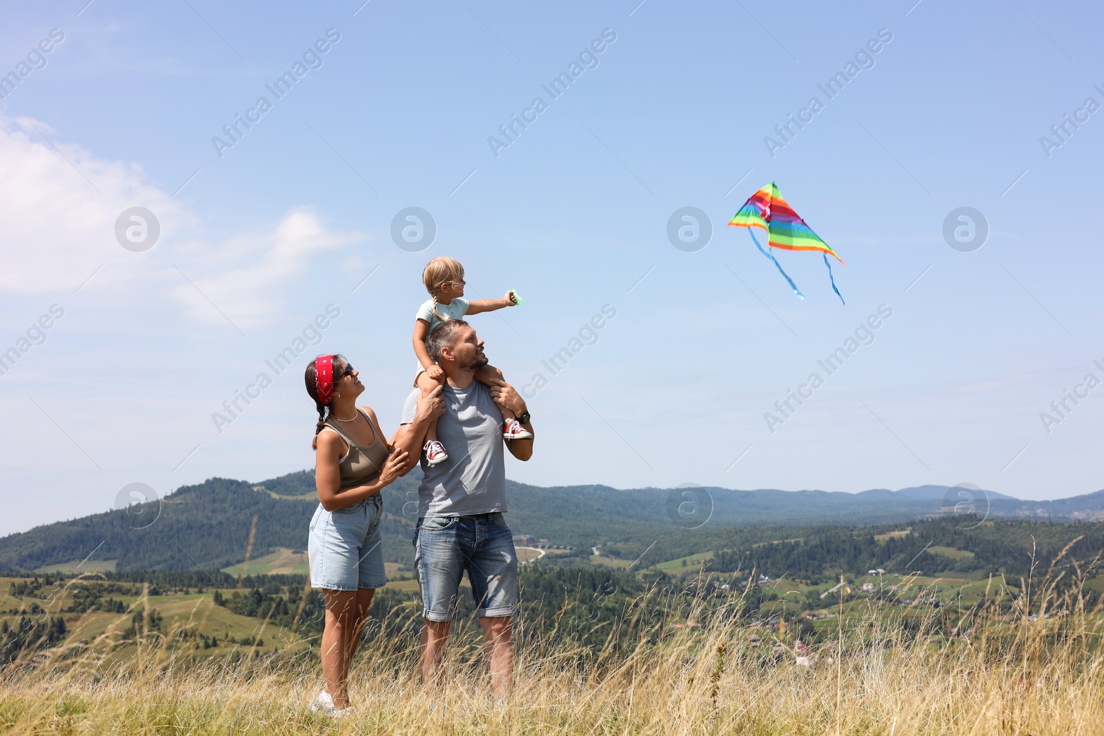 Photo of Happy family flying kite at field under blue sky