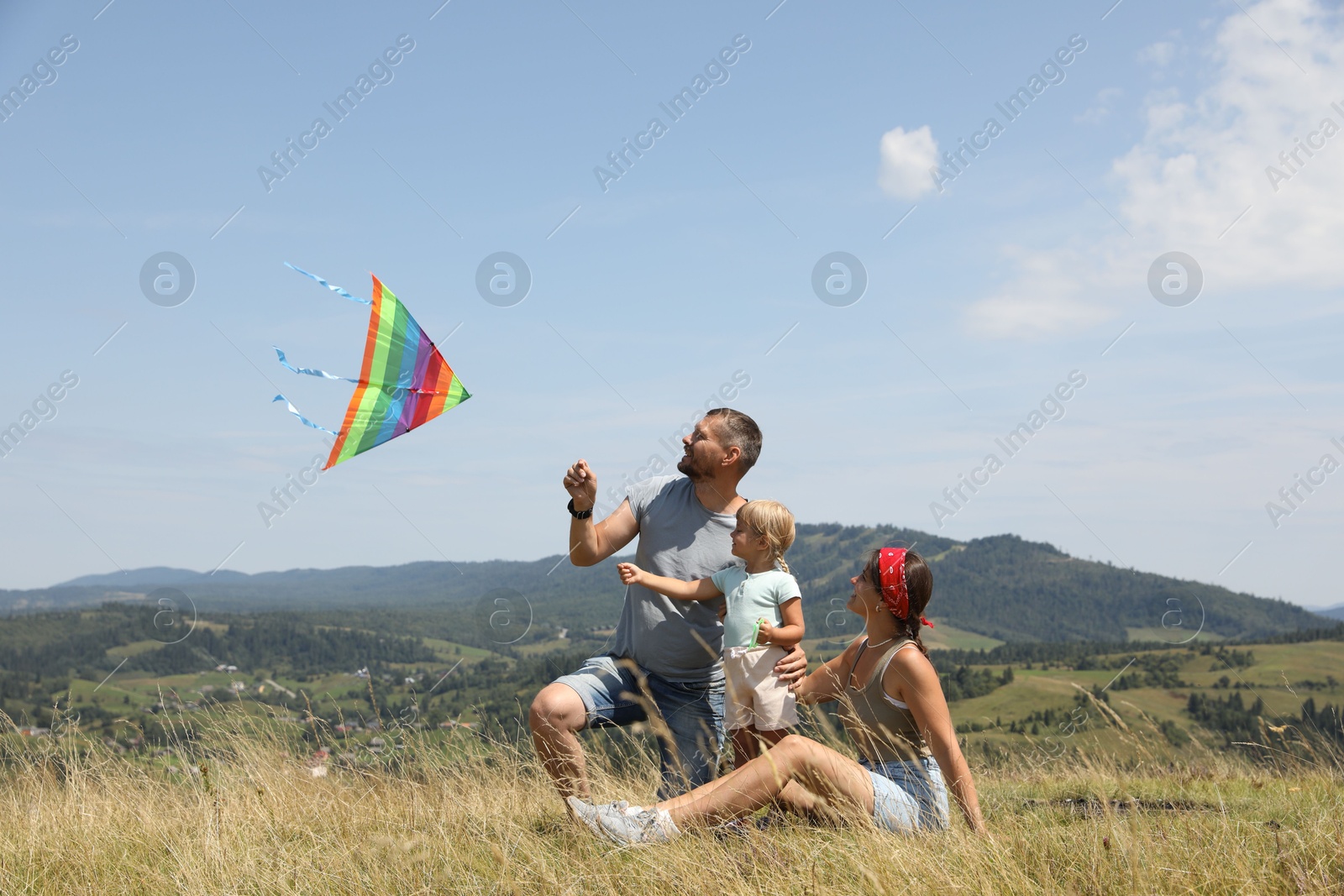 Photo of Happy family flying kite at field under blue sky