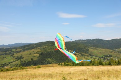 One colorful kite flying in mountains under blue sky