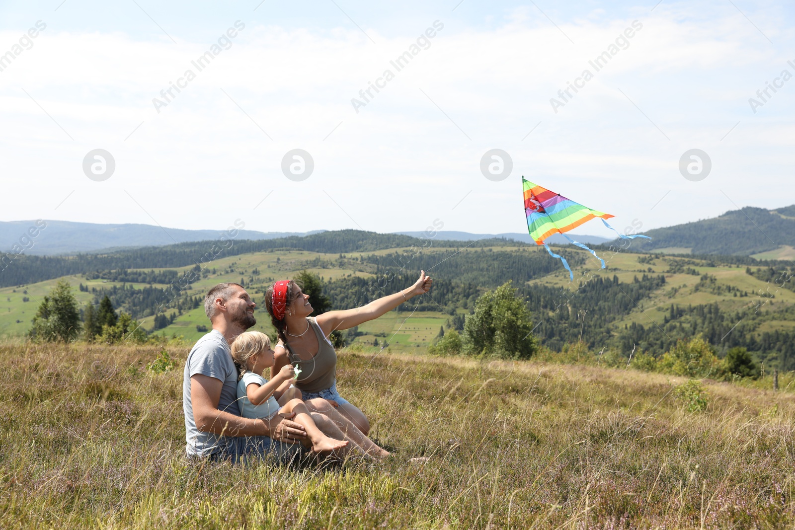 Photo of Happy family flying kite at field under blue sky