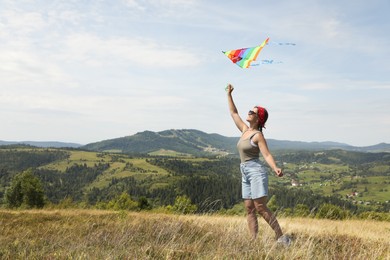 Smiling woman flying kite at field under blue sky. Space for text