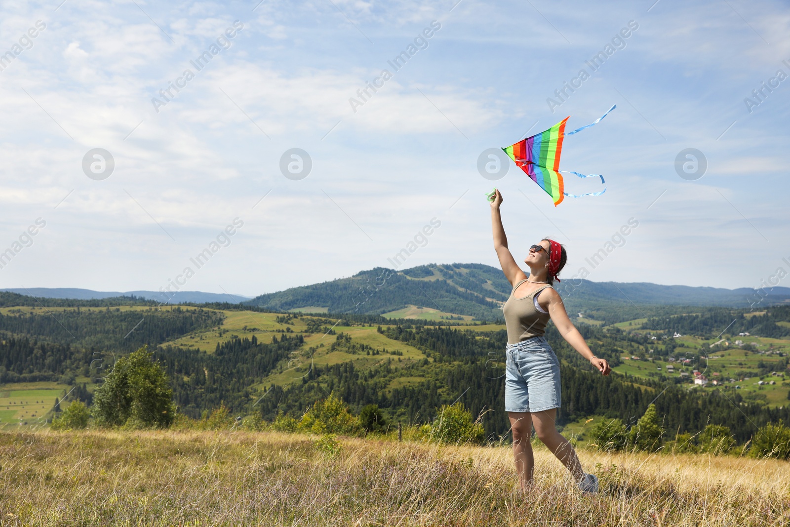 Photo of Smiling woman flying kite at field under blue sky. Space for text