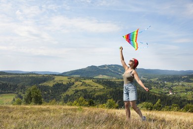 Smiling woman flying kite at field under blue sky. Space for text