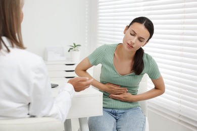 Photo of Doctor consulting patient with stomach pain at table in clinic, closeup