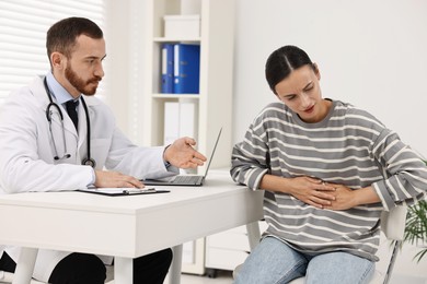 Photo of Doctor consulting patient with stomach pain at table in hospital