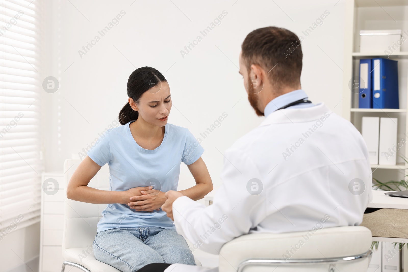 Photo of Doctor consulting patient with stomach pain in clinic