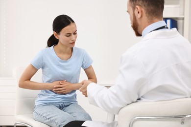 Doctor consulting patient with stomach pain in clinic