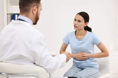 Photo of Doctor consulting patient with stomach pain in clinic