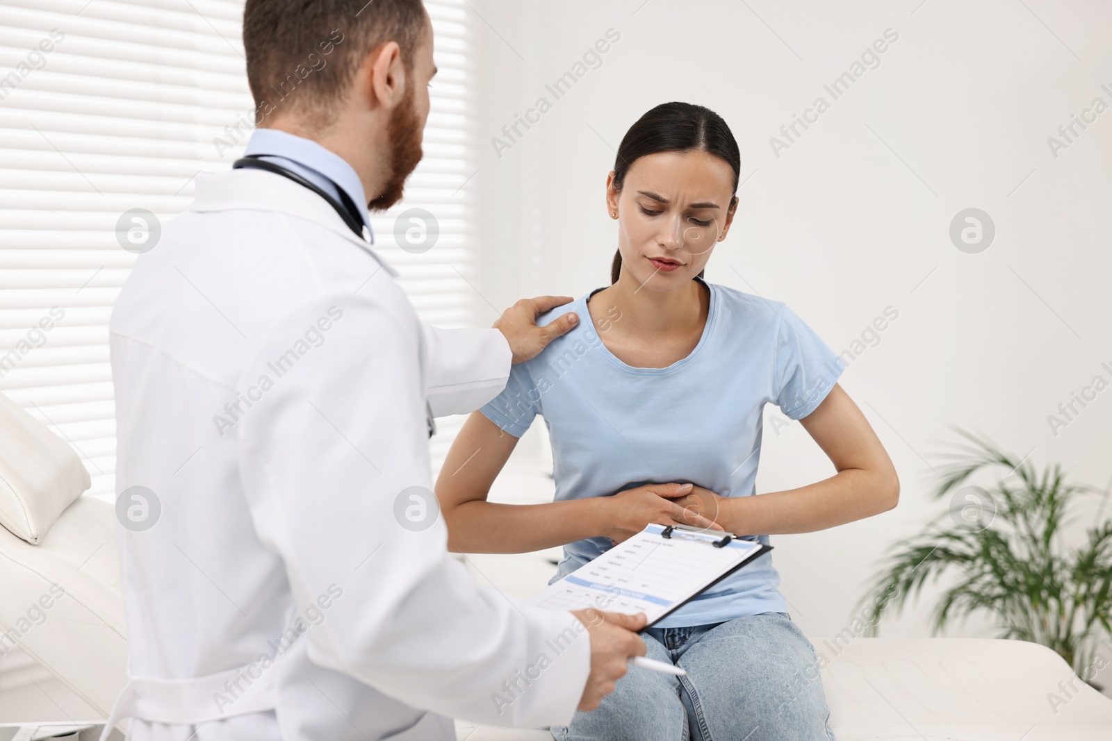 Photo of Doctor consulting patient with stomach pain in clinic