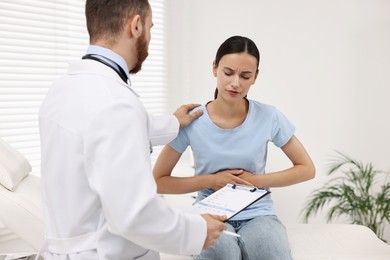 Doctor consulting patient with stomach pain in clinic