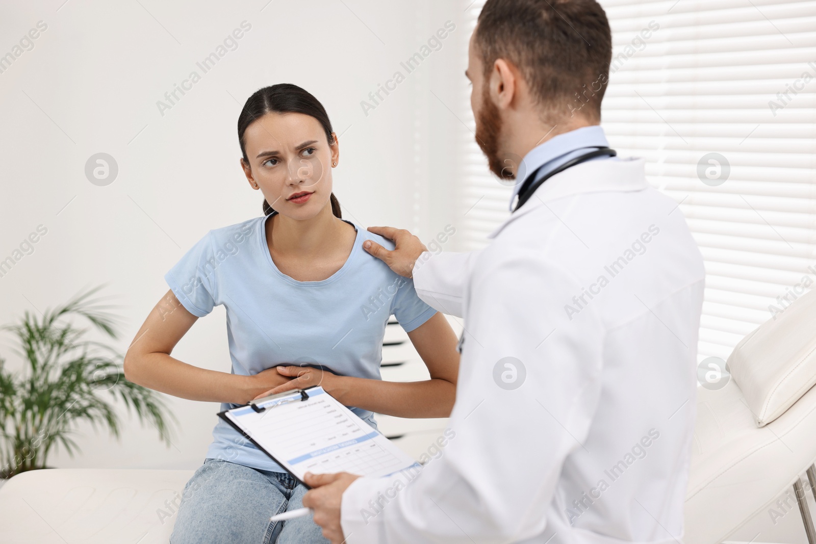 Photo of Doctor consulting patient with stomach pain in clinic