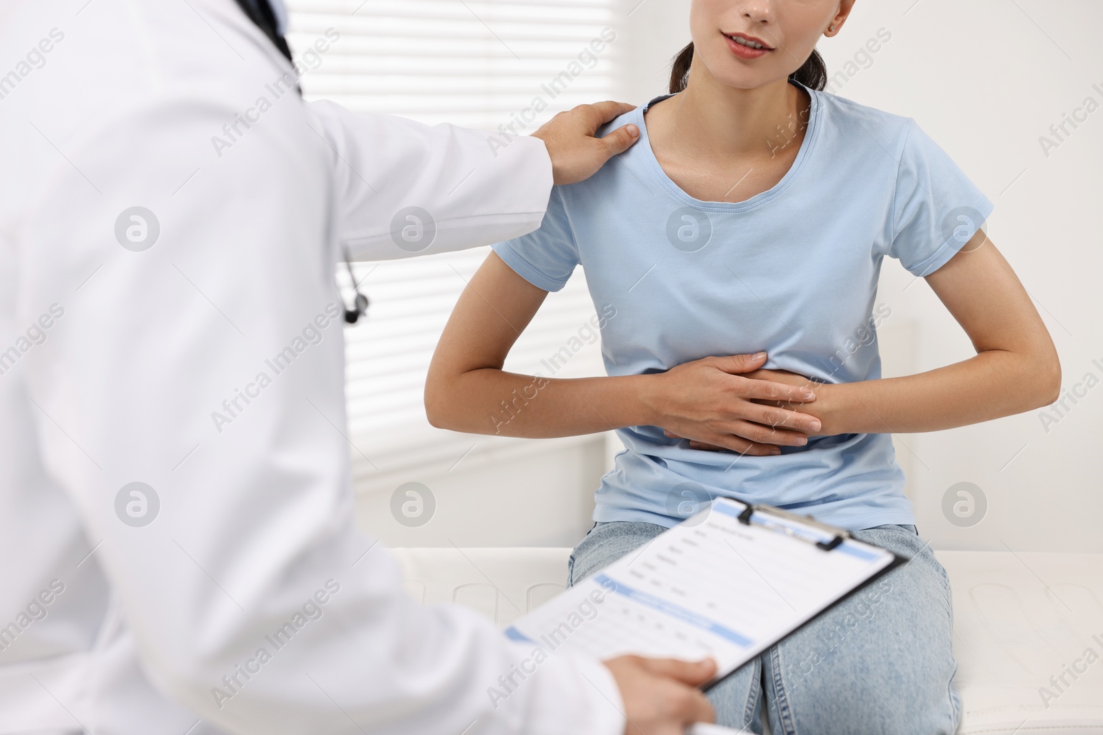 Photo of Doctor consulting patient with stomach pain in clinic, closeup