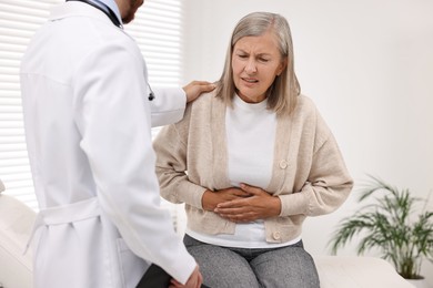 Photo of Doctor consulting senior patient with stomach pain in clinic, closeup