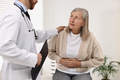 Photo of Doctor consulting senior patient with stomach pain in clinic, closeup