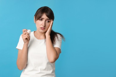 Photo of Woman with napkin suffering from sinusitis on light blue background. Space for text