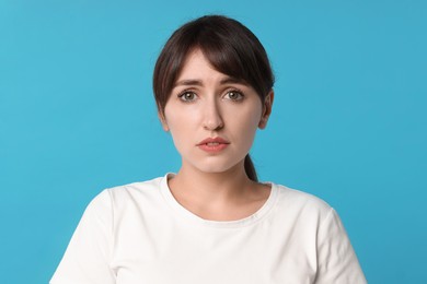 Portrait of frustrated woman on light blue background