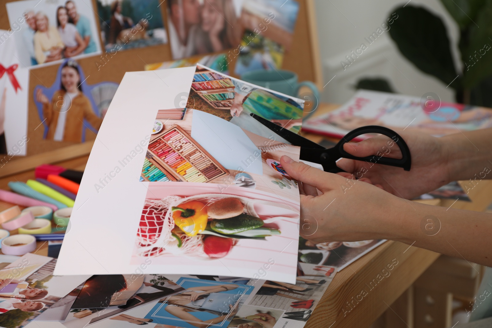 Photo of Creating vision board. Woman cutting out picture at wooden table indoors, closeup