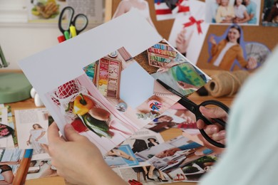 Creating vision board. Woman cutting out picture at table indoors, closeup