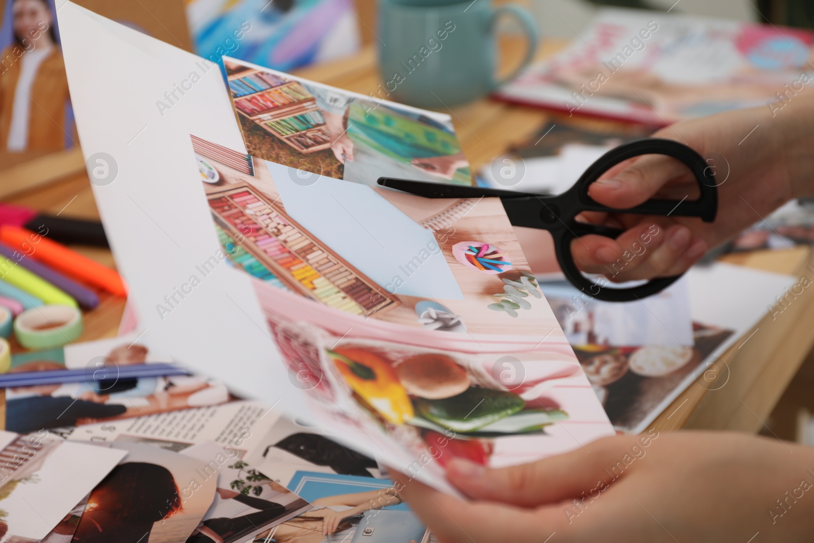 Photo of Creating vision board. Woman cutting out picture at table indoors, closeup