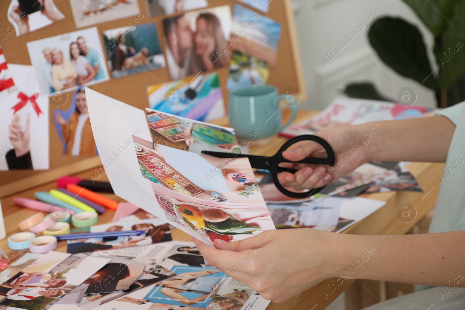 Photo of Creating vision board. Woman cutting out picture at table indoors, closeup