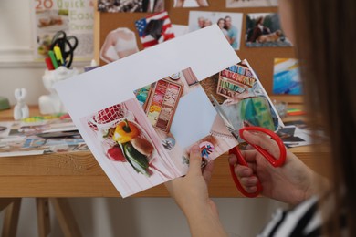 Photo of Creating vision board. Woman cutting out picture at wooden table indoors, closeup