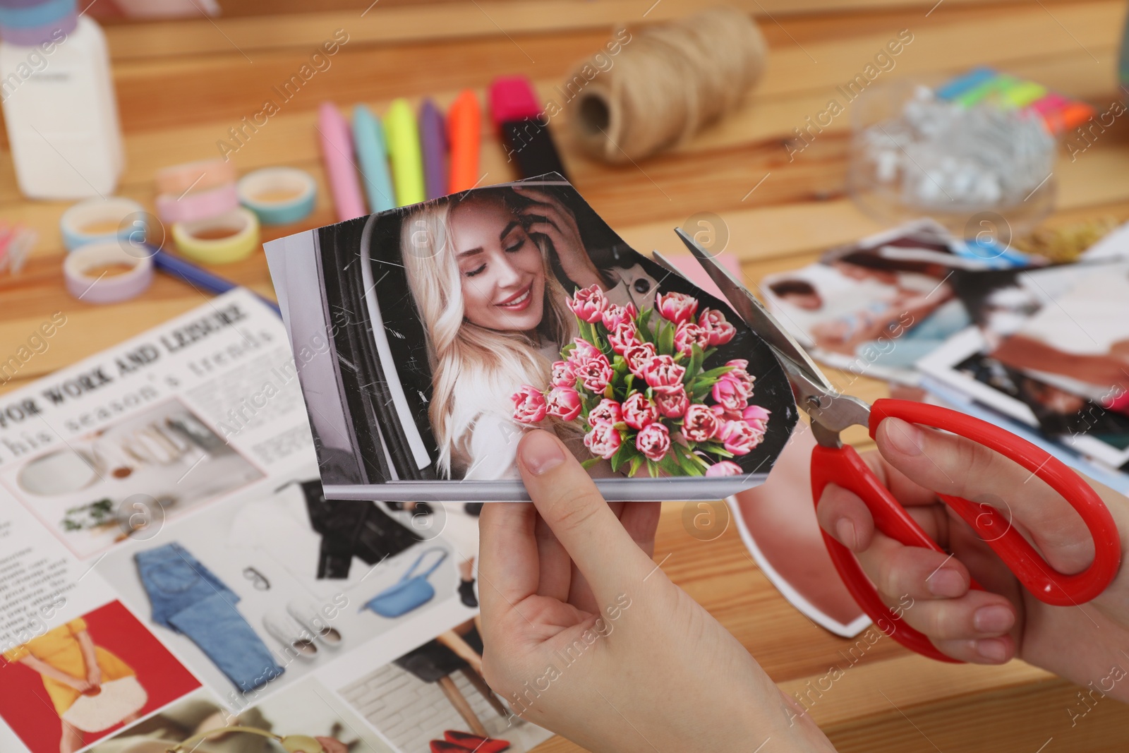 Photo of Creating vision board. Woman cutting out picture at wooden table indoors, closeup