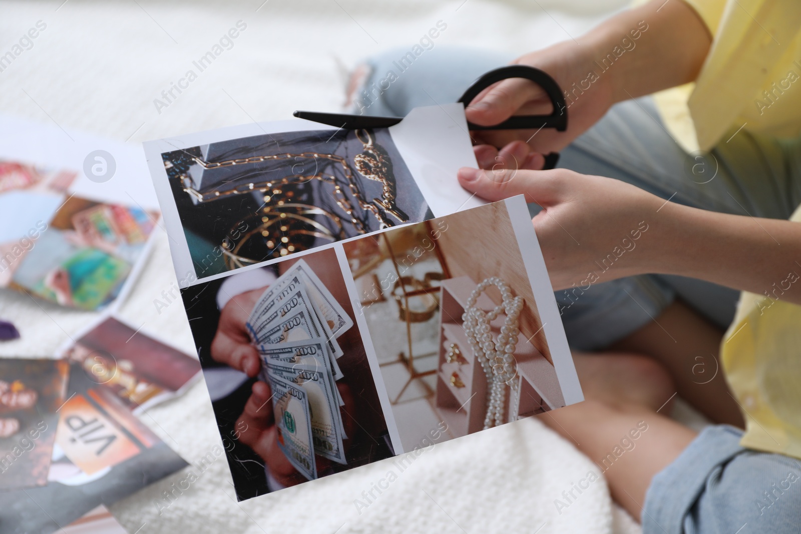 Photo of Creating vision board. Woman cutting out picture on bed indoors, closeup