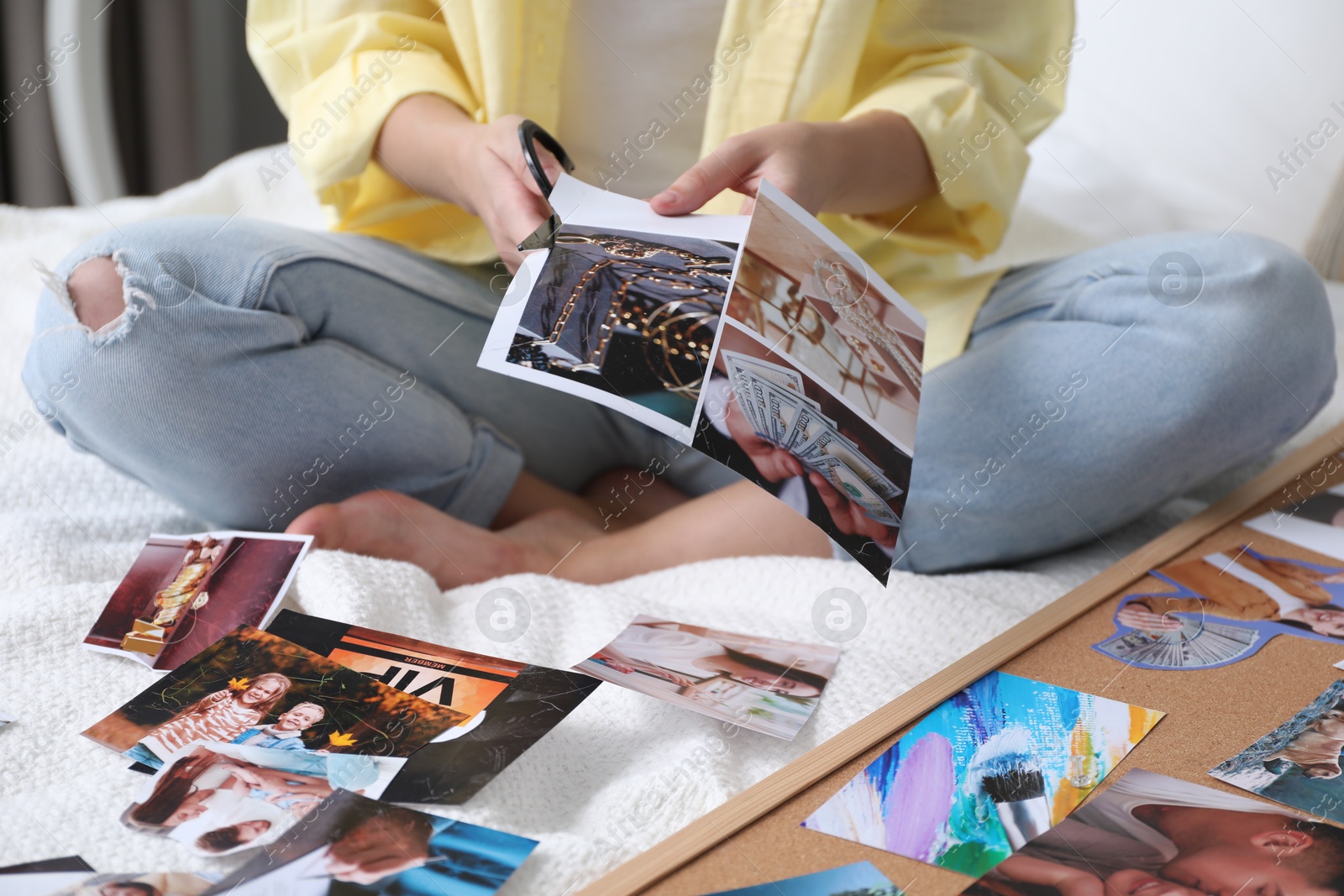 Photo of Creating vision board. Woman cutting out picture on bed indoors, closeup