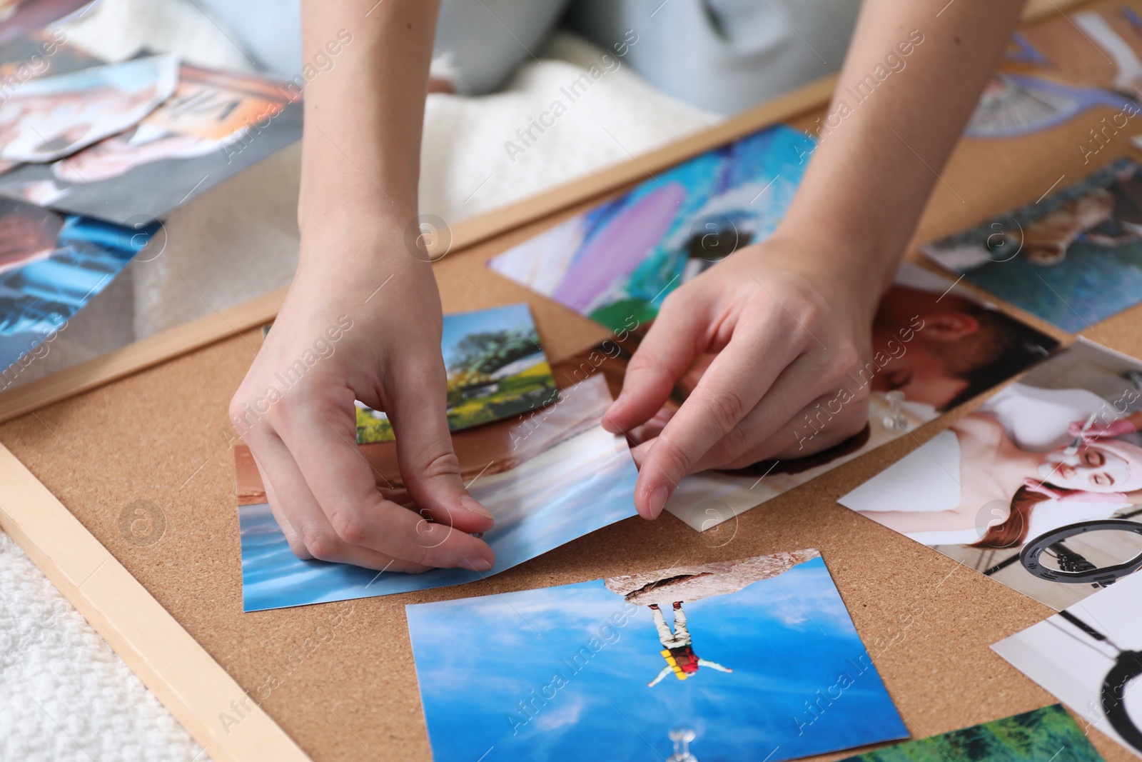 Photo of Woman creating vision board with different photos and other elements on bed indoors, closeup