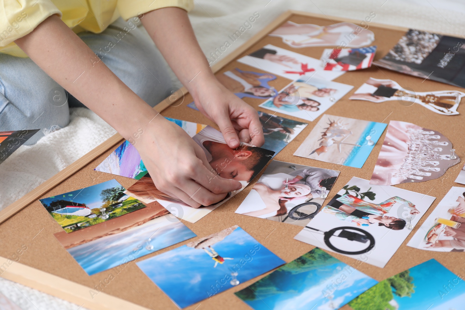 Photo of Woman creating vision board with different photos and other elements on bed indoors, closeup