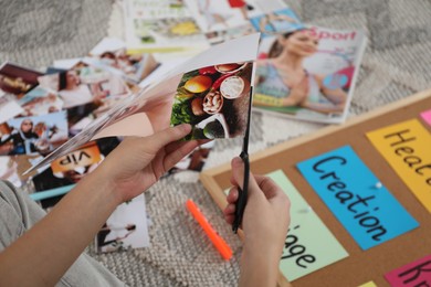 Creating vision board. Woman cutting out picture on floor indoors, closeup