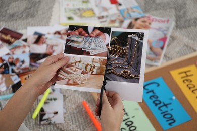 Photo of Creating vision board. Woman cutting out picture on floor indoors, closeup