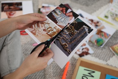 Photo of Creating vision board. Woman cutting out picture on floor indoors, closeup