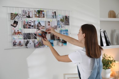 Woman creating vision board with different photos indoors