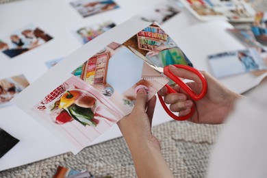 Creating vision board. Woman cutting out picture on floor indoors, closeup