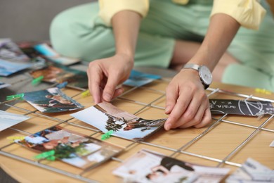 Photo of Woman creating vision board with different photos and other elements at wooden table indoors, closeup