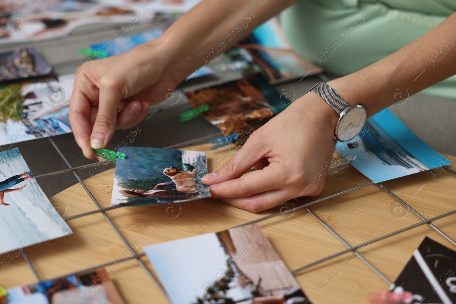 Photo of Woman creating vision board with different photos and other elements at wooden table indoors, closeup