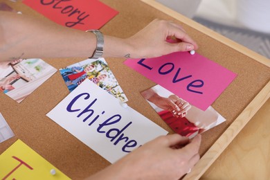 Photo of Woman creating vision with different photos and other elements board indoors, closeup